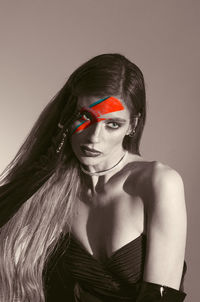 Portrait of young woman standing against wall