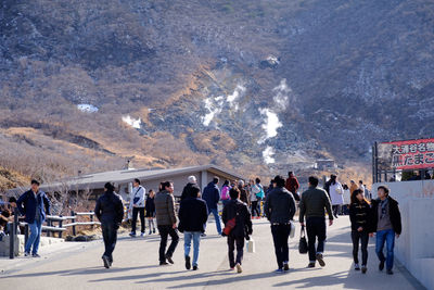 People walking on road against mountain