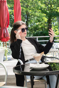 Brunette woman chatting in a smartphone at a table in a cafe