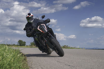 Man riding motorcycle on road against sky