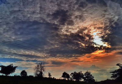 Silhouette of trees against cloudy sky