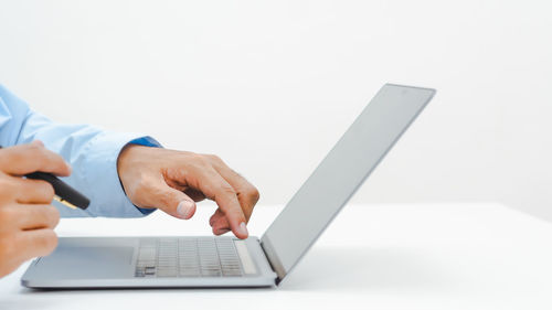 Midsection of man using smart phone against white background