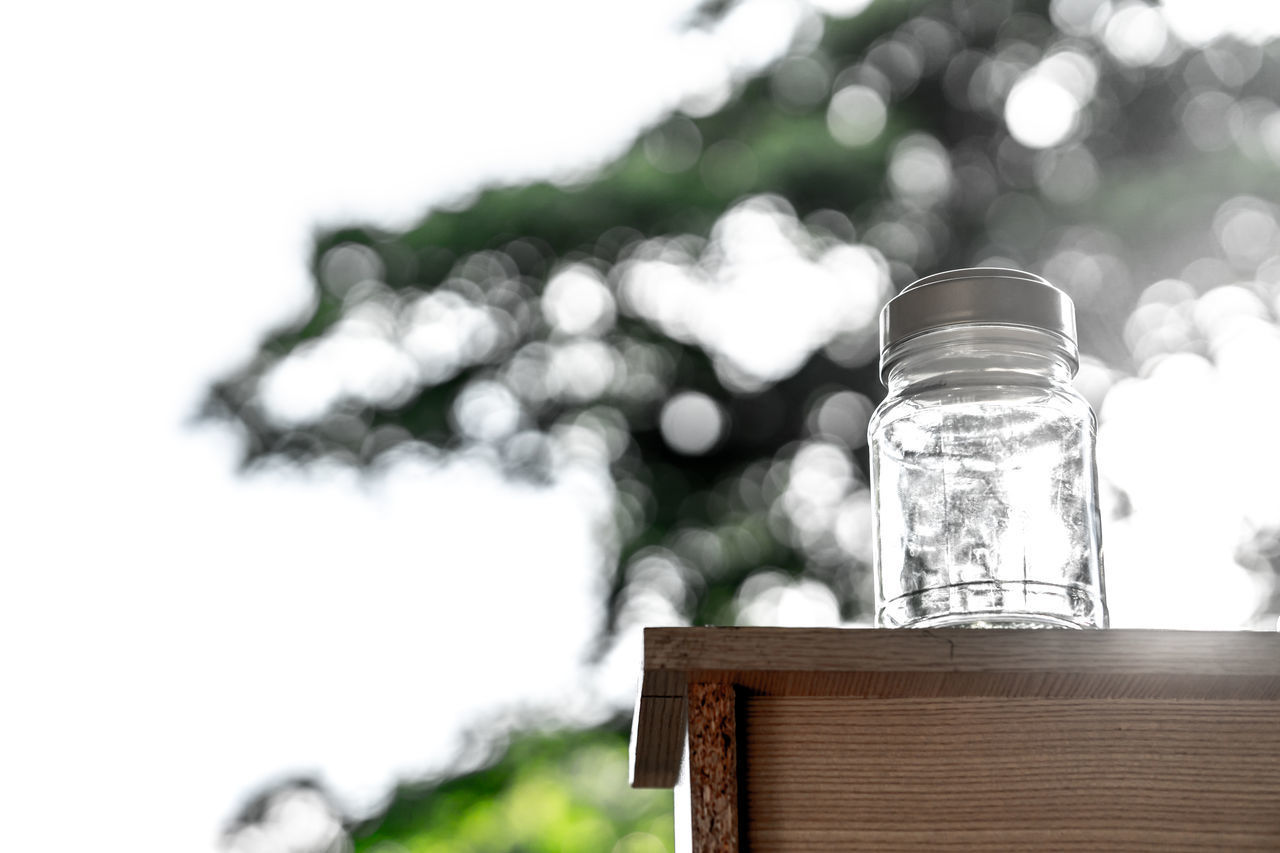 CLOSE-UP OF GLASS JAR ON TABLE AGAINST BLURRED BACKGROUND