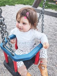 High angle view of baby girl sitting on swing at playground