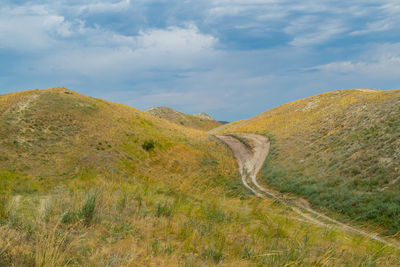 Scenic view of road by mountain against sky