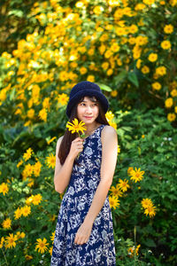 Beautiful young woman standing by yellow flower