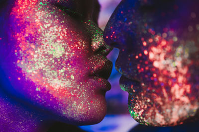 Close-up of couple with multi colored face paint kissing