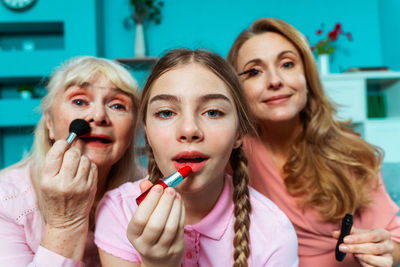 Cute girl applying lipstick with parents