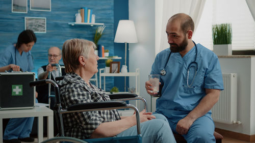 Doctor giving glass of water to patient