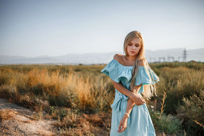 Teenage girl wearing dress standing on land against sky