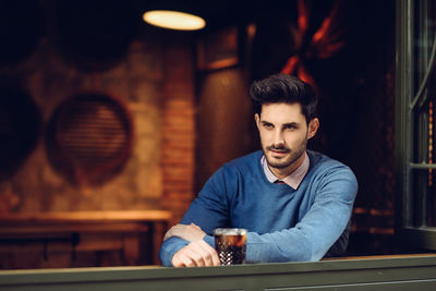 Young man having beer while sitting at table in restaurant