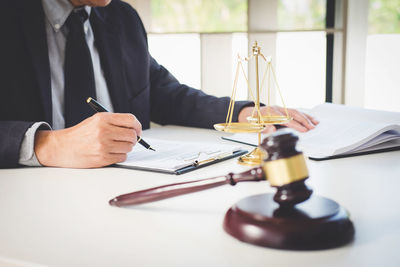 Midsection of lawyer doing paperwork at desk in courthouse