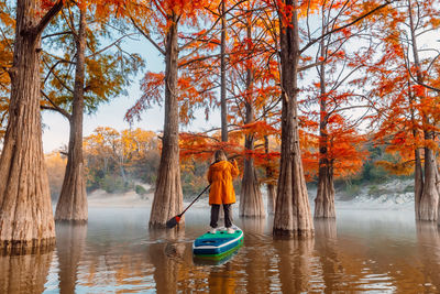 Rear view of woman standing in lake during autumn