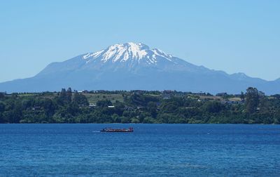 Scenic view of sea and mountains against clear blue sky