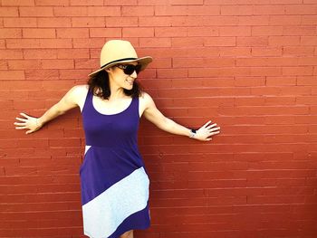 Woman wearing hat while standing against brick wall