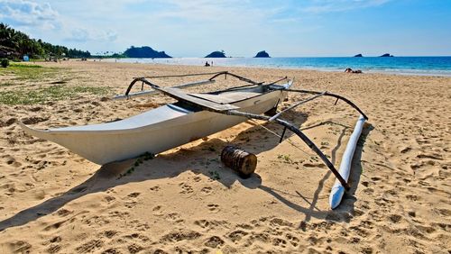 Deck chairs on shore at beach against sky