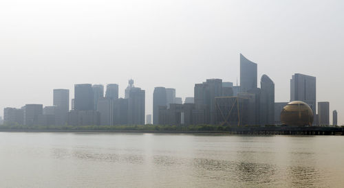 Sea by buildings against clear sky in city