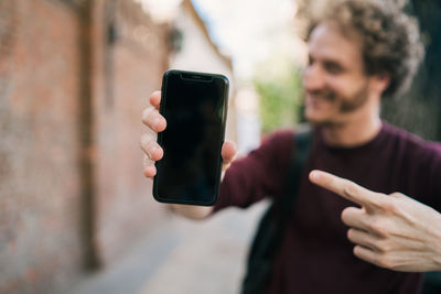 Midsection of man using mobile phone outdoors