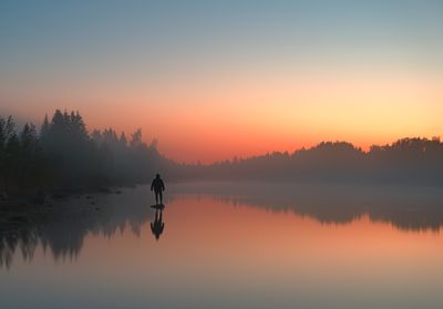 Silhouette woman standing in lake during sunset