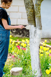 Side view of boy standing by tree trunk