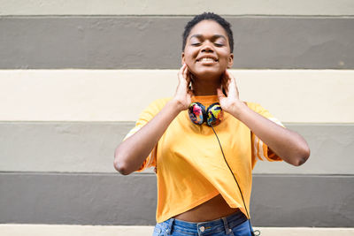 Portrait of smiling young woman standing against wall