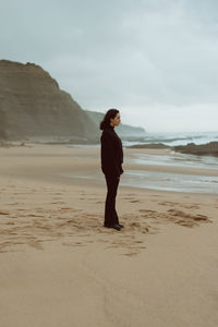 Full length of woman standing on beach against sky