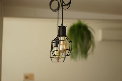 Close-up of illuminated light bulb hanging from ceiling