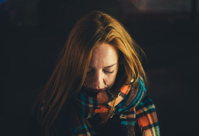 Close-up portrait of a beautiful young woman over black background