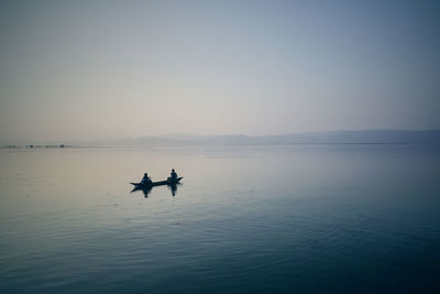 People in boat on river against clear sky