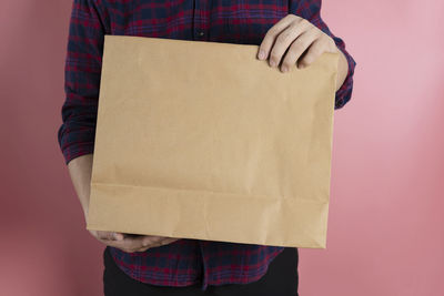 Midsection of man holding paper against white background