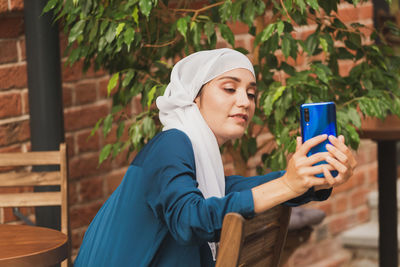 Woman taking selfie while sitting outdoors