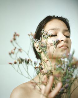 Close-up portrait of young woman with red flower