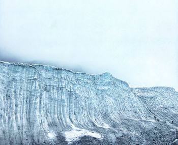 Scenic view of glacier wall against foggy sky