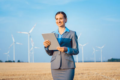 Businesswoman holding clipboard while standing on land