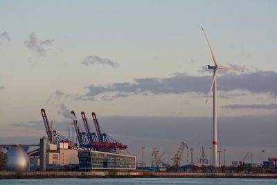 Cranes at harbor against sky