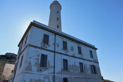 Low angle view of abandoned building against clear blue sky