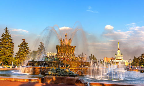 Fountain in front of building against sky