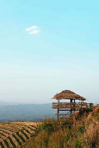 Lifeguard hut on field against blue sky