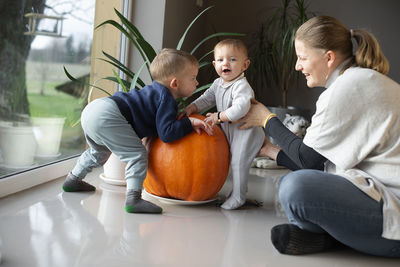 A mother playing with her two children on the floor at home