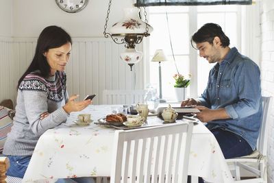 Side view of mid adult couple spending leisure time at breakfast table