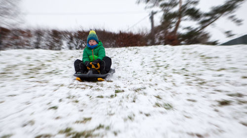 Boy tobogganing on snowcapped mountain