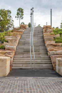 Steps amidst trees against sky