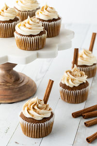 An arrangement of pumpkin spice cupcakes on a marble pedestal stand and around.