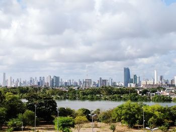 City at waterfront against cloudy sky