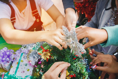 Cropped hands of family decorating christmas tree