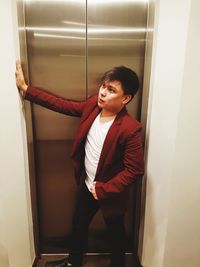 Young man standing against elevator