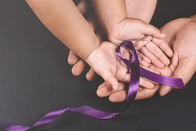 Close-up of hands holding purple over white background