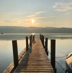 Wooden pier over sea against sky during sunset