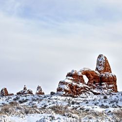 Rock formation on snow covered land against sky