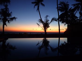 Silhouette trees by sea against sky during sunset